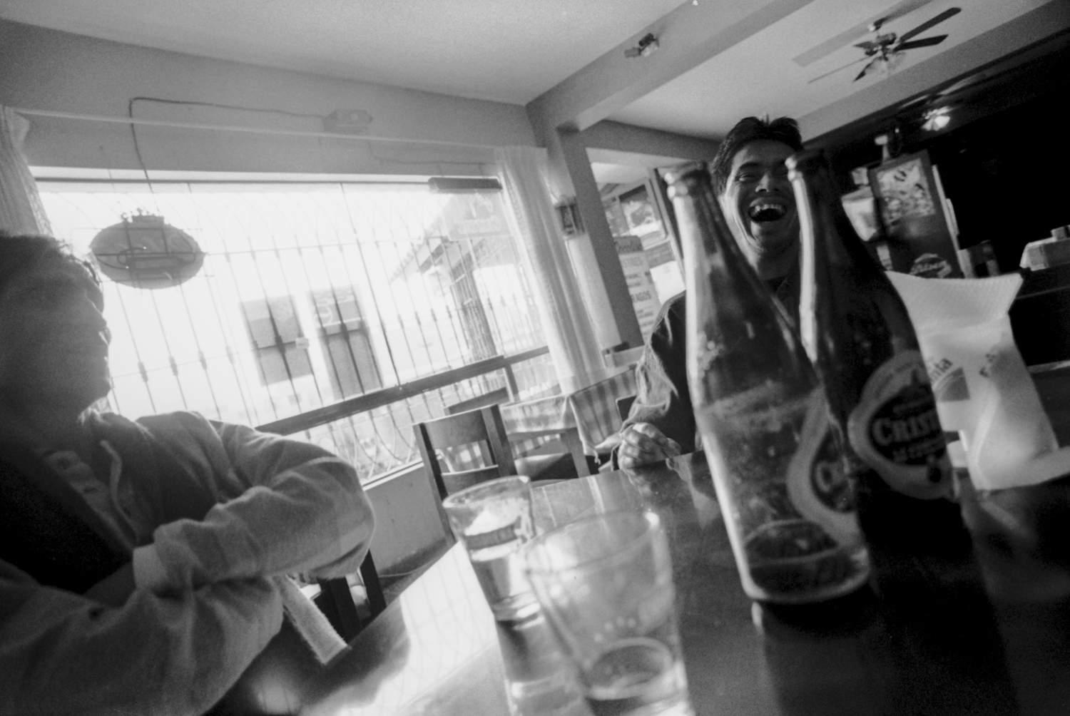 Julio, 1996. Lucho Jara (izquierda) y Lorenzo, su pareja (derecha) ríen mientras beben cerveza en una pollería de San Juan de Miraflores.